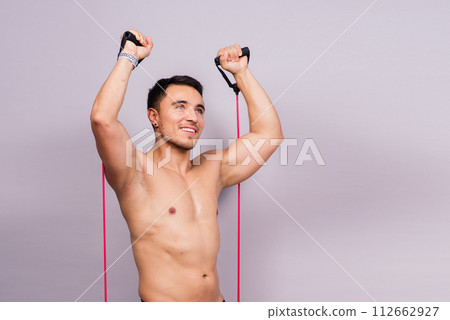 Young handsome man during workout with a resistance rubber bands. Shoulder lateral raise exercise. 112662927