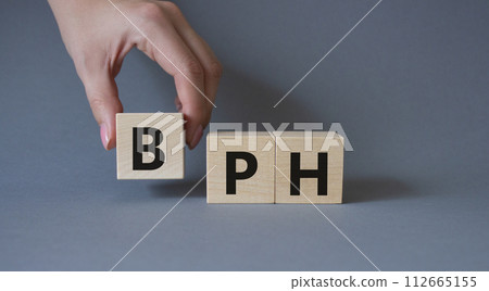 BPH - Benign Prostatic Hyperplasia symbol. Wooden cubes with word BPH. Businessman hand. Beautiful grey background. Medical and BPH concept. Copy space. BPH - Benign Prostatic Hyperplasia symbol. Wooden cubes with word BPH. Businessman hand. Beautiful grey background. Medical and BPH concept. Copy space. 112665155