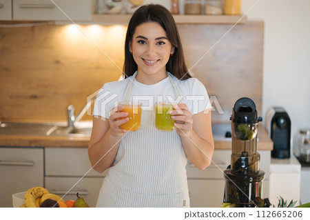 Portrait of beautiful woman holding two glasses of different beverage in hands. Healthy vegan drink  112665206