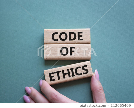 Code of ethics symbol. Concept words Code of ethics on wooden blocks. Beautiful grey green background. Businessman hand. Business and Code of ethics concept. Copy space. Code of ethics symbol. Concept words Code of ethics on wooden blocks. Beautiful grey green background. Businessman hand. Business and Code of ethics concept. Copy space. 112665409