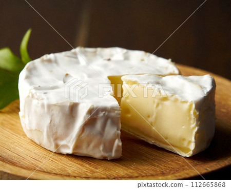 Cut camembert cheese on a wooden board 112665868