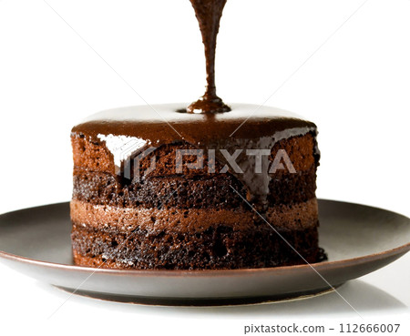 The moment when melted chocolate is poured on a rich chocolate cake 112666007