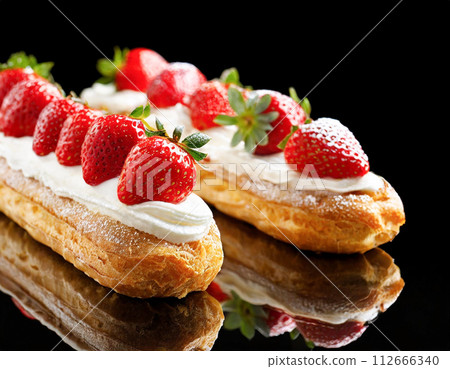 Eclairs topped with strawberries and fresh cream 112666340