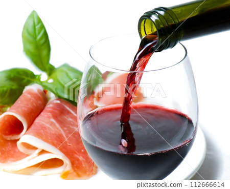 Raw ham and red wine poured into a wine glass Raw ham and red wine poured into a wine glass 112666614