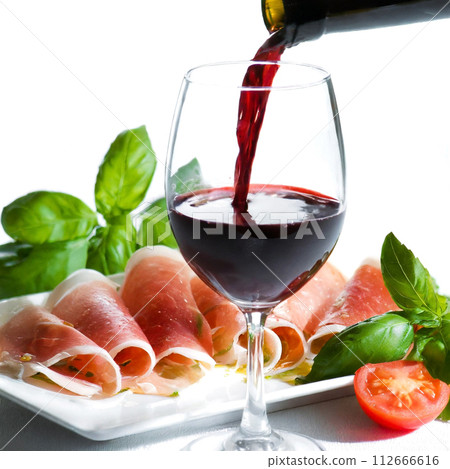 Raw ham and red wine poured into a wine glass Raw ham and red wine poured into a wine glass 112666616