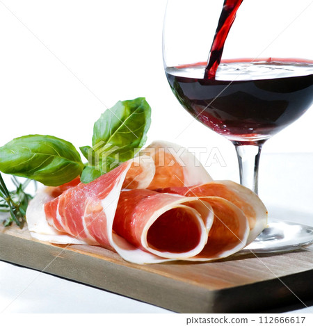 Raw ham and red wine poured into a wine glass Raw ham and red wine poured into a wine glass 112666617