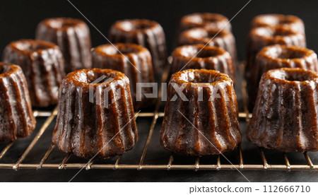 Many canelés de Bordeaux lined up on a wire mesh Many canelés de Bordeaux lined up on a wire mesh 112666710
