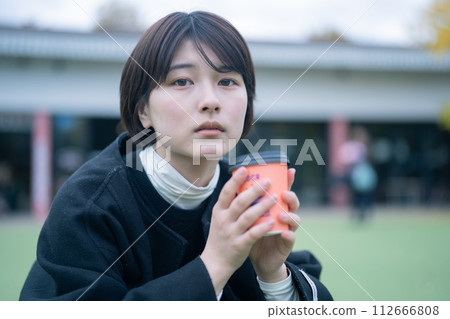 Woman drinking coffee outdoors Woman drinking coffee outdoors 112666808