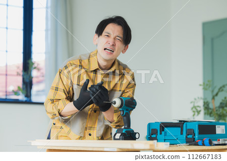 一個年輕人用電動螺絲起子工作 112667183