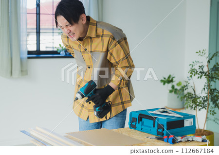 一個年輕人用電動螺絲起子工作 112667184