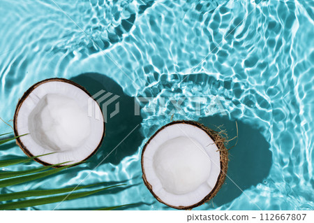 Summer background with coconuts on water background with water splashes. Creative summer background for design. Coconut cosmetics. Summer background with coconuts on water background with water splashes. Creative summer background for design. Coconut cosmetics. 112667807