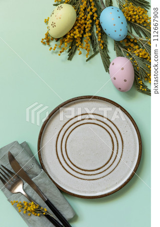 Table setting for Easter dinner with easter eggs and mimosa on a pastel background. Table setting for Easter dinner with easter eggs and mimosa on a pastel background. 112667908
