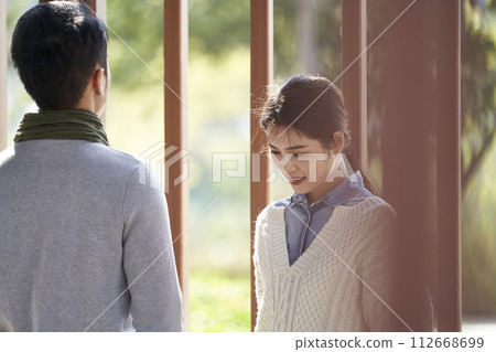 young asian couple talking chatting outdoors in city park 112668699