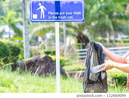 A woman cleans up by picking up plastic bottles at a natural park. Concept of protecting the environment, saving the world, recycling, reducing global warming, Earth Day. close up, blurred background A woman cleans up by picking up plastic bottles at a natural park. Concept of protecting the environment, saving the world, recycling, reducing global warming, Earth Day. close up, blurred background 112669094