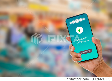 A man's hand holds a smartphone on screen with message Payment Successful in a supermarket. Concept of financial transactions with mobile devices. Closeup, money, transfer, online. blurred background A man's hand holds a smartphone on screen with message Payment Successful in a supermarket. Concept of financial transactions with mobile devices. Closeup, money, transfer, online. blurred background 112669153