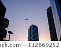 Airplane flying between buildings at dusk 112669252