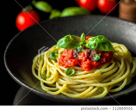 Basil and tomato pasta on a black plate 112669501