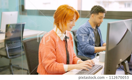 Colleagues working happily together in a coworking space Colleagues working happily together in a coworking space 112670053