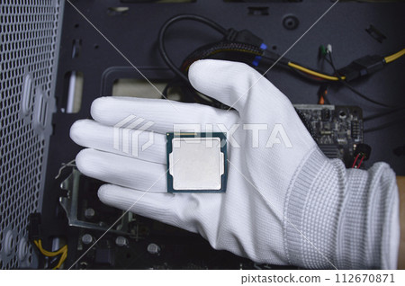 Picture of a hand wearing white gloves with a CPU chip placed on it. 112670871