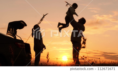 Silhouette of father tossing child in air. Family traveling by car having fun in nature laughing smiling enjoying life. Happy moments together. Loving dad with daughter and wife at weekend travel trip Silhouette of father tossing child in air. Family traveling by car having fun in nature laughing smiling enjoying life. Happy moments together. Loving dad with daughter and wife at weekend travel trip 112671671
