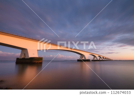Zeeland bridge, Netherlands. A long bridge over the sea during sunset. Long exposure photo. 112674033