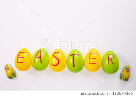 Word Easter is written on the eggs. Easter eggs on white background. Greetings card, Happy Easters. Flat lay ,top view Word Easter is written on the eggs. Easter eggs on white background. Greetings card, Happy Easters. Flat lay ,top view 112674366