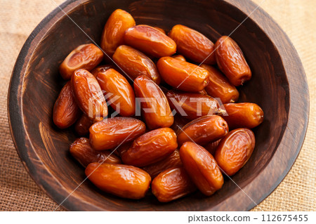 Dried date fruits in rustic wooden bowl. Sweet natural Turkish dessert. Organic product 112675455