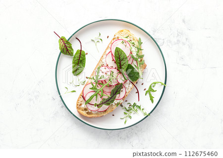 Radish sandwiches with cottage cheese and fresh green leaves, top down view 112675460