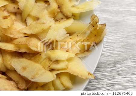 Potato peel on white kitchen plate. Food waste close up 112675463