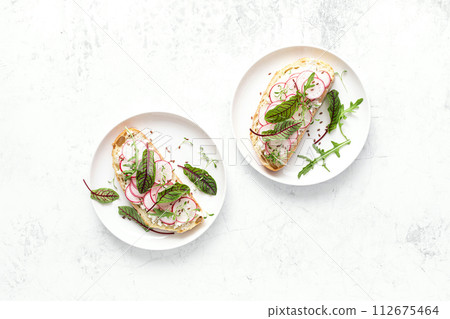Radish sandwiches with cottage cheese and fresh green leaves, top down view 112675464