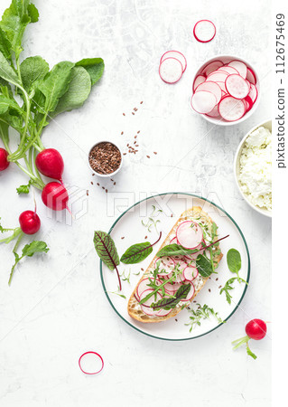 Radish sandwiches with cottage cheese and fresh green leaves, top down view 112675469