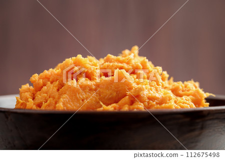 Hot mashed sweet potatoes with steam in wooden bowl. Healthy vegetable puree close up Hot mashed sweet potatoes with steam in wooden bowl. Healthy vegetable puree close up 112675498