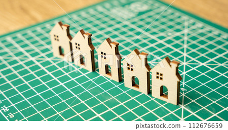 Miniature houses on a cutting mat. Home renovation and reconstruction concept. Construction of real estate and new housing. Maintenance house. Close up, selective focus 112676659