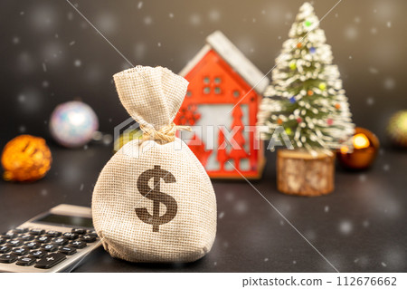 Dollars money bag on the background of a Christmas tree, house and snow. Accumulating money and planning a budget. Business and finance. Loans, deposit, credit. Promotions, offers. Xmas winter holiday Dollars money bag on the background of a Christmas tree, house and snow. Accumulating money and planning a budget. Business and finance. Loans, deposit, credit. Promotions, offers. Xmas winter holiday 112676662