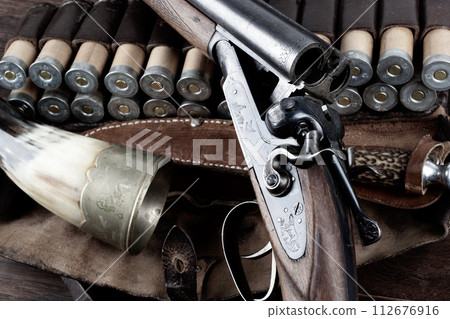 double barreled side shotgun with cartridges in bandolier. double barreled side shotgun with cartridges in bandolier. 112676916