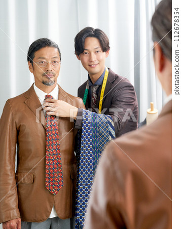 顧客和店員在鏡子前選擇領帶 112678354