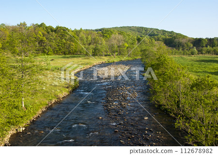 A clear stream flowing through a farm in Hokkaido 112678982