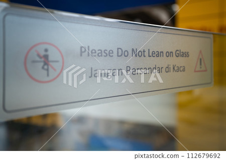 "Please Do Not Lean On Glass" sticker on the glass railing. 112679692
