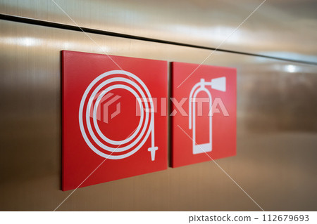 Fire Hose and fire extinguisher signs on the wall 112679693