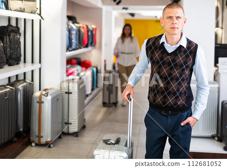 Positive man chose suitcase in haberdashery store Positive man chose suitcase in haberdashery store 112681052