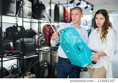 Couple choosing travel suitcase in shop 112681167