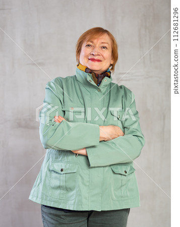 Senior woman standing confidently dressed in warm clothes with smile full of cheer 112681296