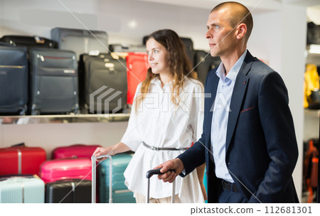 Portrait of respectable couple with suitcases in haberdashery store Portrait of respectable couple with suitcases in haberdashery store 112681301