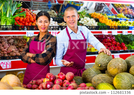 Smiling sellers recommending organic produce at farmers market 112681336