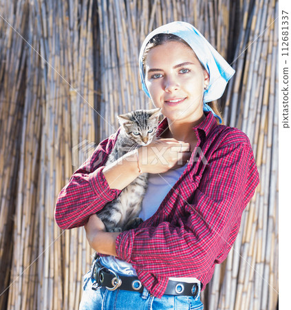 Portrait of a farm girl holding a kitten in her arms 112681337
