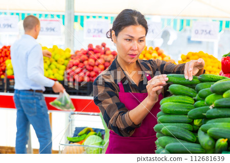 Female greengrocery owner preparing fruits and vegetables for sale on counter 112681639