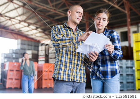Female manager discussing order list with male worker at warehouse 112681691