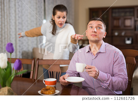 Man ignoring disgruntled wife reprimanding him Man ignoring disgruntled wife reprimanding him 112681726