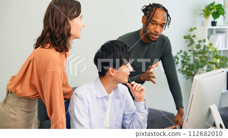 Multinational people talking while looking at a computer in the office 112682010