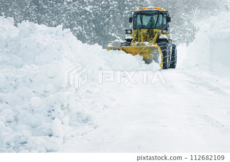 Snowplow removing snow from a road with heavy snow Snowplow removing snow from a road with heavy snow 112682109